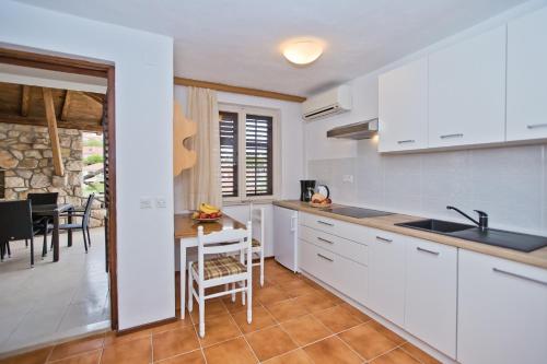 a kitchen with white cabinets and a table and chairs at Castle Štambuk in Hvar