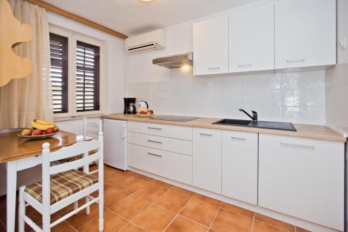 a kitchen with white cabinets and a wooden table at Castle Štambuk in Hvar