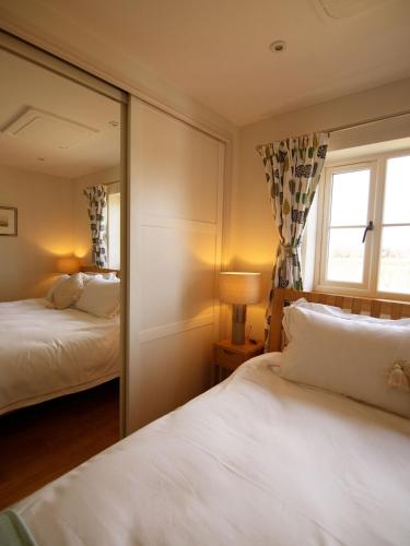 a bedroom with two beds and a mirror at Walwyn Court Barns in Ledbury