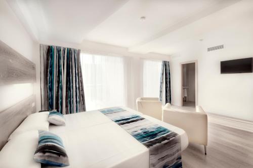 a white bedroom with a bed and a window at Hotel Gracia in El Arenal