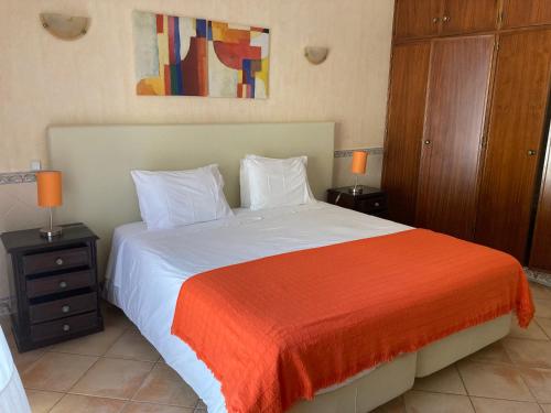 a bedroom with a large bed with an orange blanket at Residencia Julio in Sagres