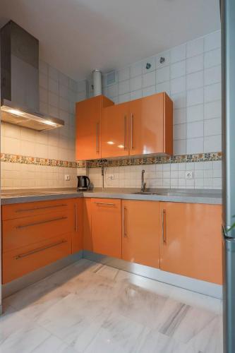 a kitchen with orange cabinets and a sink at corazon de triana in Seville
