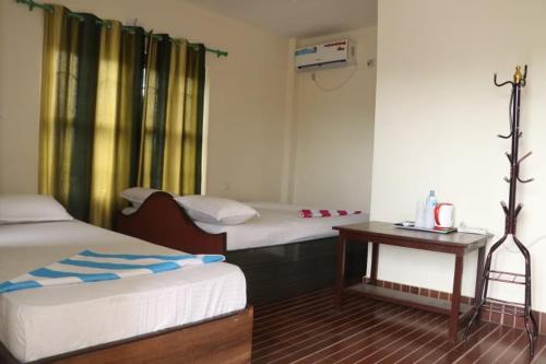 a hotel room with two beds and a table at Green Tree in Chitwan