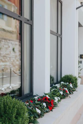 a row of windows with red and white flowers at Hôtel Le Roquebrune in Roquebrune-Cap-Martin