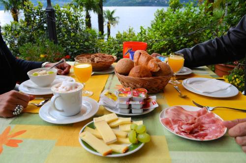 Hotel Garni Rivabella au Lac في بريساغو: طاولة مع وجبة الإفطار من المواد الغذائية والمشروبات