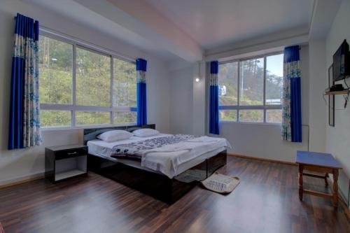 a bedroom with a bed and two large windows at Aura Homes in Gangtok