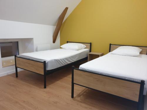 2 camas en una habitación con paredes amarillas en Gîte Lepetit Sabotier grande capacité Puy de Dôme, en Giat