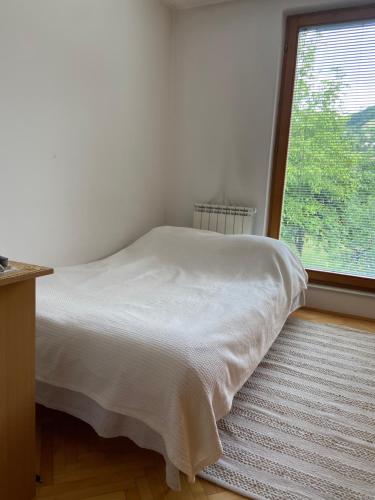 uma cama branca num quarto com uma grande janela em Sarajevo Apartment Lovely em Sarajevo