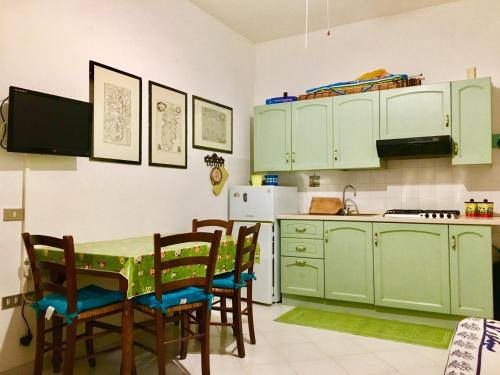 kuchnia z zielonymi szafkami oraz stołem i krzesłami w obiekcie La conchiglia w mieście Villasimius