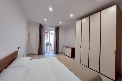 a white bedroom with a large bed and a dresser at Casa Adelina - Appartamento Pallanza centro in Verbania