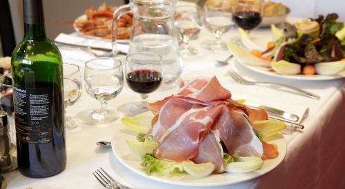 a table with plates of food and a bottle of wine at Hôtel Le Méditerranée in Lourdes