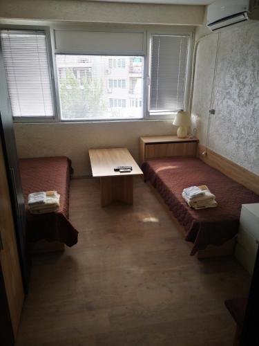een kamer met 2 bedden, een tafel en 2 ramen bij Studio- Krasi in Varna