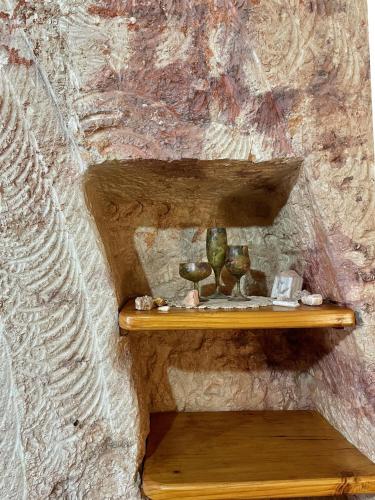 a wall with two wooden shelves with vases on them at Ali's Underground Studio in Coober Pedy