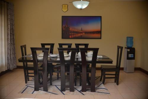 坎帕拉的住宿－Nile Estates Villa Kiwatule，一间用餐室,配有黑色的桌子和椅子
