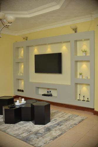 a living room with a flat screen tv on a wall at Nile Estates Villa Kiwatule in Kampala