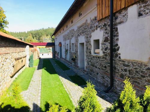 a courtyard of a stone building with a green lawn at Selská chalupa Anetka in Horšovský Týn