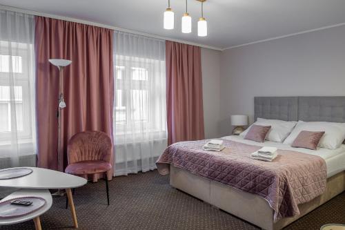 a bedroom with a bed and a table and a chair at Kamienica Pod Neptunem in Puck
