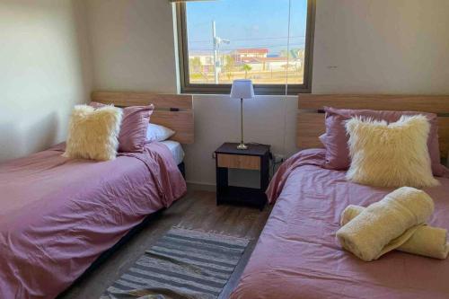 1 dormitorio con 2 camas con sábanas rosas y ventana en Espectacular casa en bahía inglesa!, en Bahía Inglesa