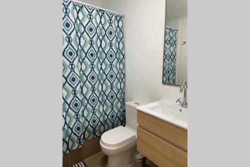a bathroom with a toilet and a sink and a shower curtain at Espectacular casa en bahía inglesa! in Bahia Inglesa