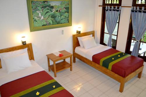 a hotel room with two beds and a table at Flamboyan Hotel in Kuta