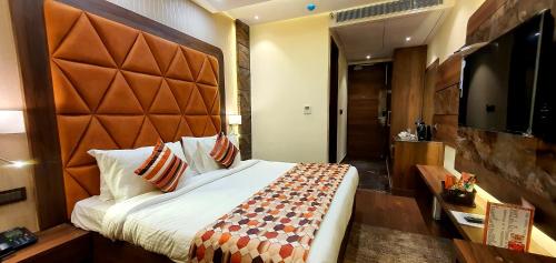 a hotel room with a large bed and a television at Hotel Makhan Residency in Amritsar