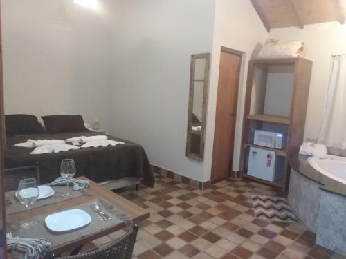 a room with a bed and a table and a sink at Chalés Recanto Vista do Valle in Monte Verde