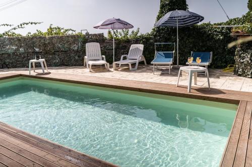 a swimming pool with chairs and umbrellas on a deck at Venere B&B Castelmola in Castelmola