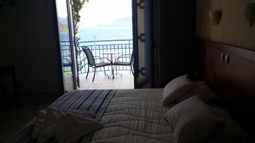 a bedroom with a bed with a view of the ocean at Olive Bay Hotel in Ayia Evfimia