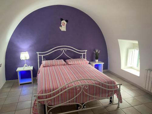 Un dormitorio con una cama con una pared morada. en CASA DIAMANTIK, en Martina Franca