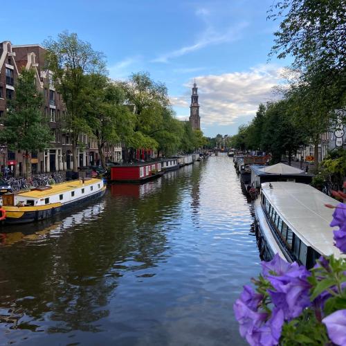 a canal with boats and a clock tower in the distance at Houseboat Bonnie in Amsterdam