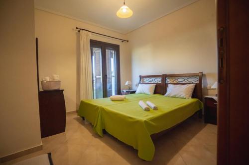 a bedroom with a green bed with two towels on it at VILLA KAROLINA Tsogkas in Syvota