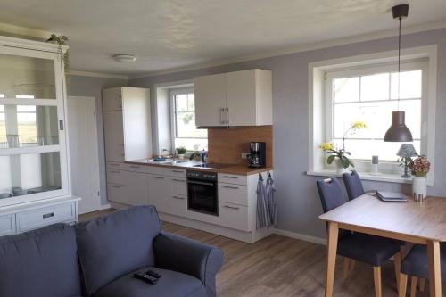 a kitchen with a table and a blue couch and a dining room at Ferienwohnung SteifeBrise in Ockholm