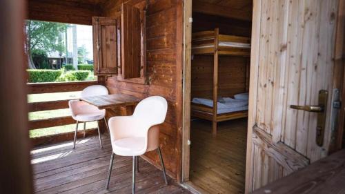 Camping Divoká Voda في براتيسلافا: كابينة خشبية مع كراسي وطاولة وسرير بطابقين