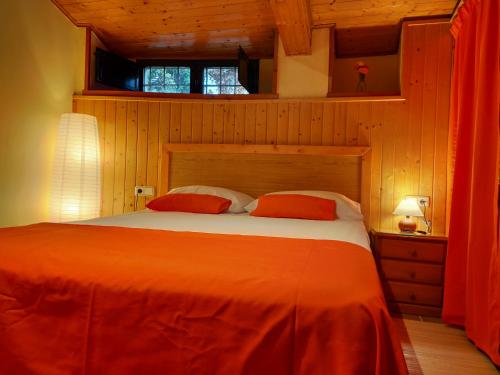 ein Schlafzimmer mit einem Bett mit einer orangefarbenen Bettdecke in der Unterkunft Senda Verde do Salnés in Portas