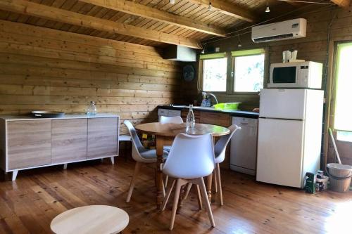 une cuisine avec une table et un réfrigérateur blanc dans l'établissement Ma petite cabane Gites des oliviers, à La Roque-sur-Cèze