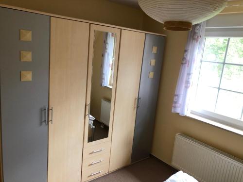 Schlafzimmer mit einem Schrank mit einem Spiegel und einem Fenster in der Unterkunft Kapitänshaus Scharmberg, Ferienwohnung Möwe in Born