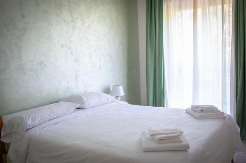 a bedroom with a white bed with towels on it at Sport Hotel & Residence Il Bivacco del Parco in Cutura