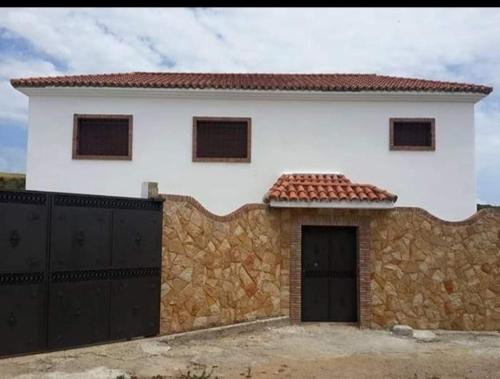 a white house with a stone wall and a garage at Villa Haidra in Dar Merah Deriba