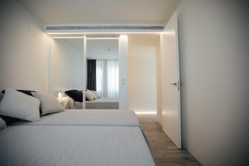 a bedroom with a white bed and a mirror at BN SUITES Rambla in Alicante