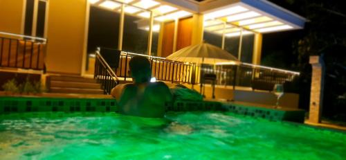 a man sitting in a swimming pool at night at Mountain View Anapoima in Anapoima