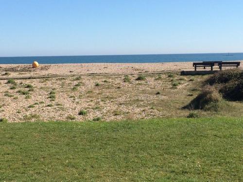 a bench on a beach with the ocean in the background at Pagham Getaways in Pagham