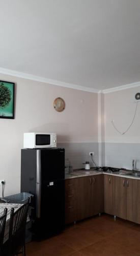 a kitchen with a refrigerator and a microwave on the wall at Apartment Ureki in Ureki