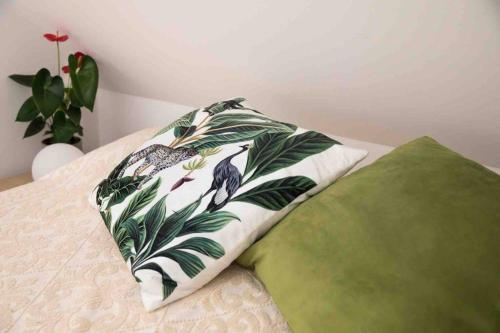 a pillow on top of a bed with a plant at Stay Veszprèm, modern city center flat in Veszprém