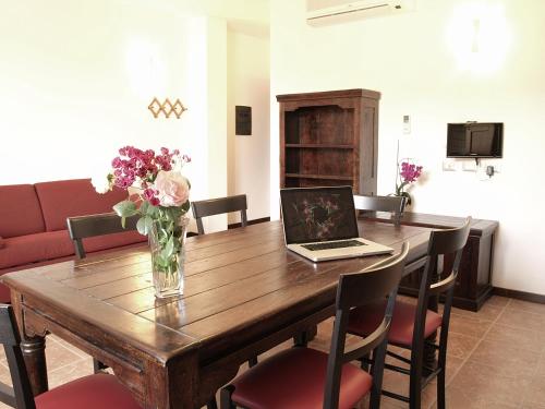 a dining room table with a laptop and flowers on it at Residenza Locci - Rooms & Apartments in Teulada