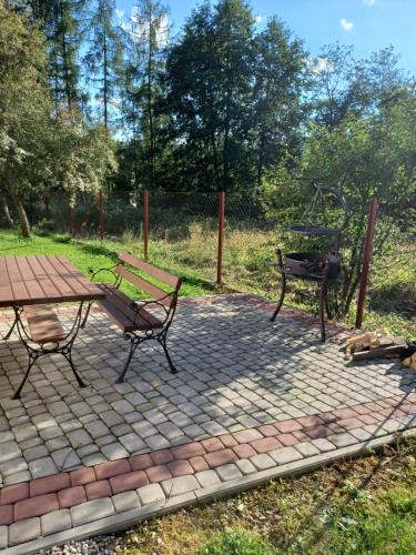 una mesa de picnic y un banco en un patio de ladrillo en Zacisze, en Biały Dunajec