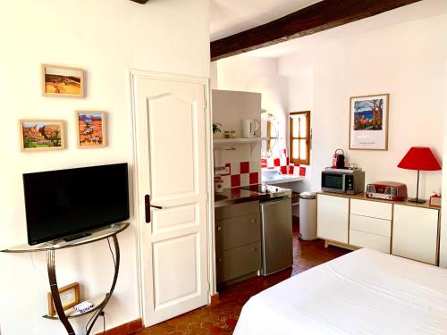 a living room with a television and a kitchen at le 1835, studio rouge-Corail in Moustiers-Sainte-Marie