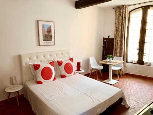 une chambre avec un lit avec des oreillers rouges et blancs dans l'établissement le 1835, studio rouge-Corail, à Moustiers-Sainte-Marie