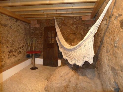 a hanging hammock in a room with a stone wall at Casa da Rua Nova in Castelo de Vide