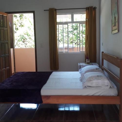 a bed in a room with two windows at Pousada Sossego da Vila - Trindade Paraty in Trindade