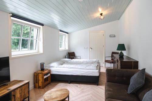 ein Schlafzimmer mit einem Bett, einem Sofa und einem Tisch in der Unterkunft Eikenschors in Veere